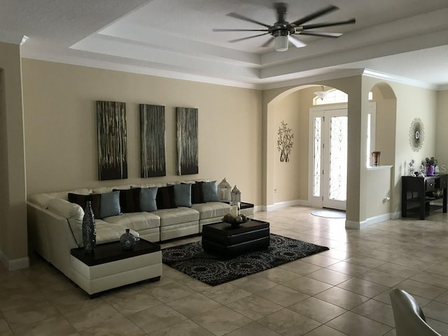 living room featuring light tile patterned floors, a raised ceiling, ceiling fan, and crown molding