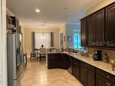 kitchen featuring light stone countertops, hanging light fixtures, a notable chandelier, stainless steel fridge, and dishwashing machine