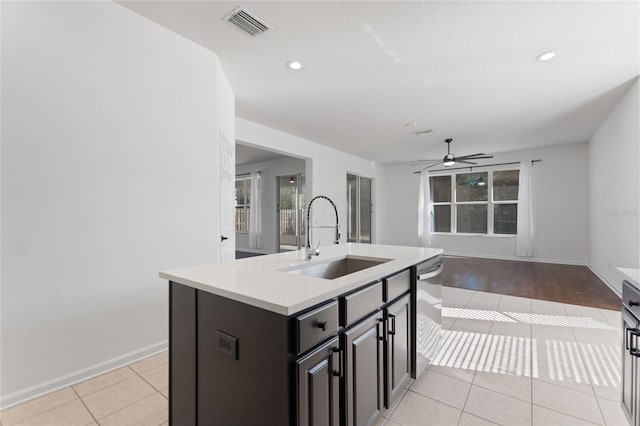 kitchen featuring ceiling fan, dishwasher, sink, an island with sink, and light tile patterned floors