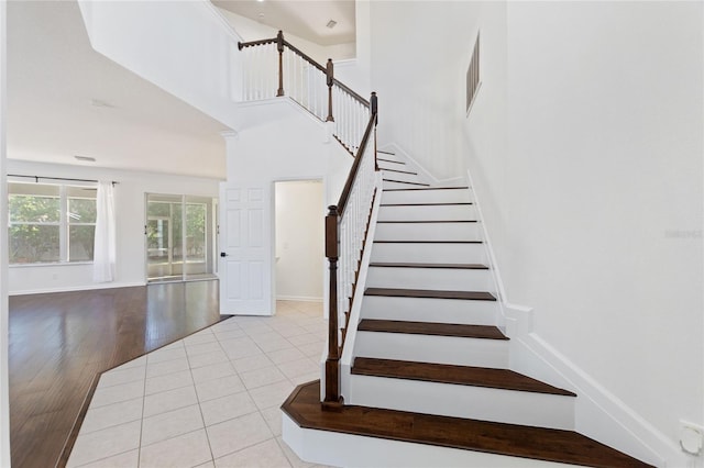 stairway featuring tile patterned flooring and a high ceiling