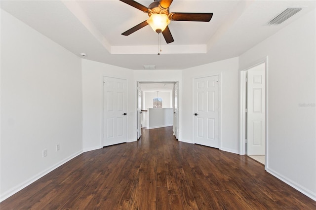 unfurnished room featuring dark hardwood / wood-style floors, ceiling fan, and a tray ceiling