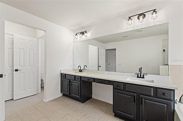 bathroom with tile patterned flooring, vanity, a textured ceiling, and toilet