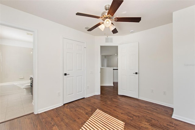 unfurnished bedroom featuring connected bathroom, ceiling fan, and dark wood-type flooring