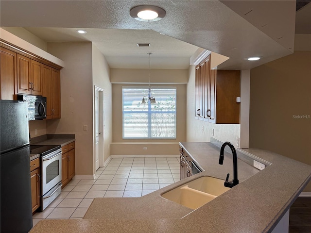 kitchen with decorative light fixtures, sink, light tile patterned floors, black appliances, and a textured ceiling