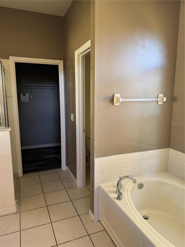 bathroom with toilet, tile patterned flooring, and a tub