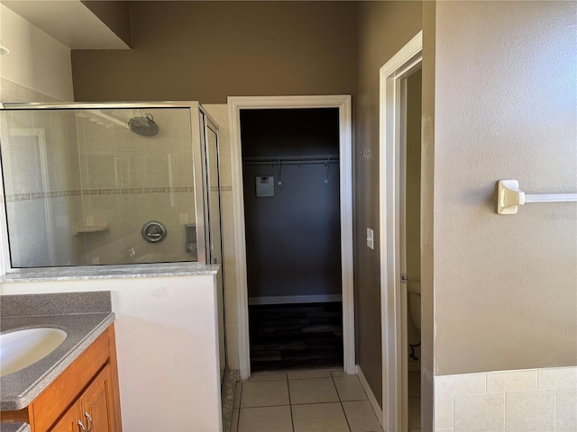 bathroom featuring vanity, toilet, an enclosed shower, and tile patterned flooring