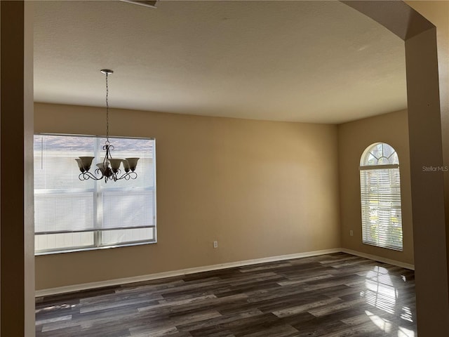 unfurnished dining area featuring an inviting chandelier and dark hardwood / wood-style flooring