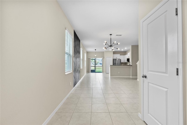 hallway featuring light tile patterned flooring and a notable chandelier