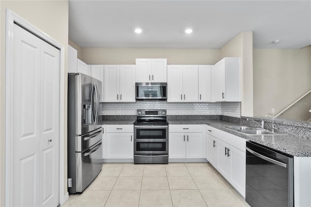 kitchen with sink, decorative backsplash, light tile patterned floors, white cabinetry, and stainless steel appliances