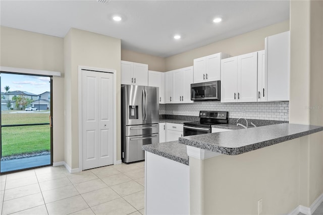 kitchen with kitchen peninsula, decorative backsplash, light tile patterned floors, white cabinetry, and stainless steel appliances