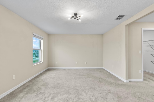 empty room featuring light colored carpet and a textured ceiling