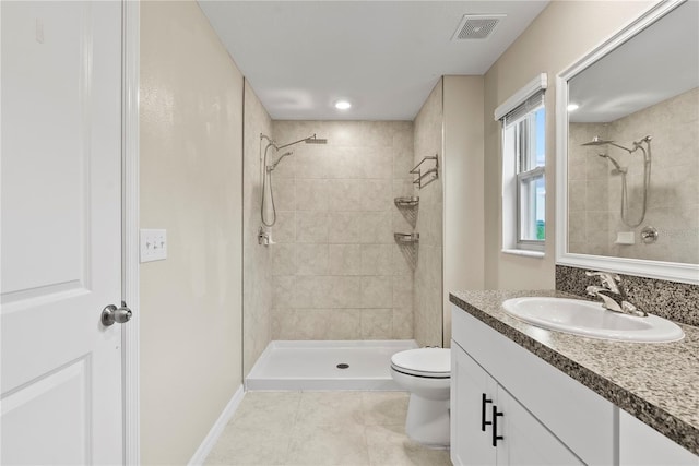 bathroom with a tile shower, tile patterned floors, vanity, and toilet