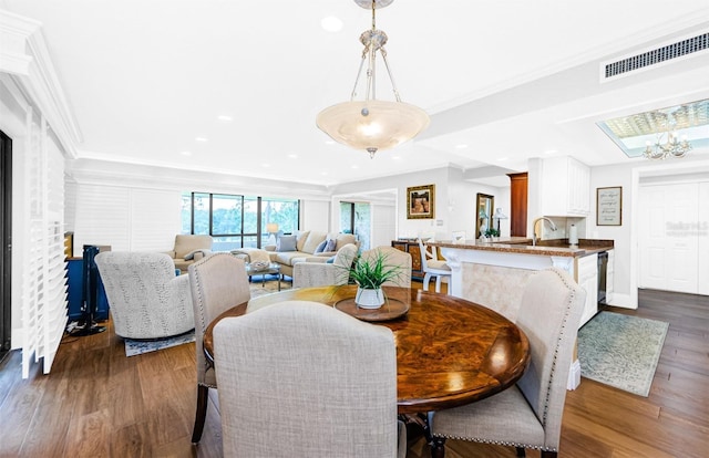 dining space featuring an inviting chandelier, crown molding, and dark wood-type flooring