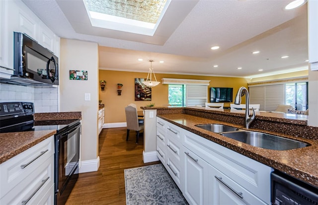 kitchen featuring dark hardwood / wood-style flooring, backsplash, dark stone counters, black appliances, and white cabinets