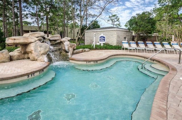 view of swimming pool with pool water feature and a patio area