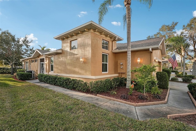 view of side of home featuring stucco siding, a lawn, and cooling unit