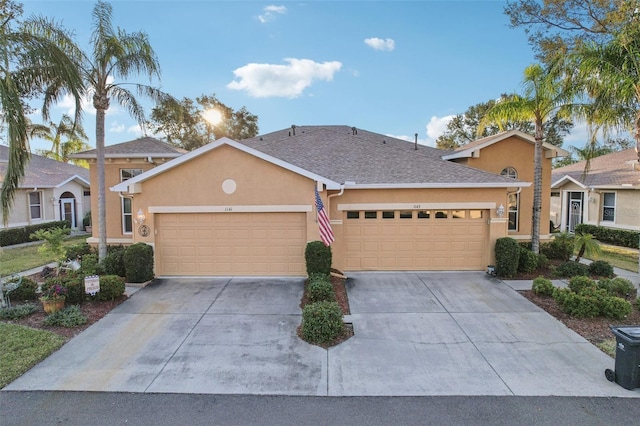 ranch-style home with stucco siding, concrete driveway, an attached garage, and a shingled roof