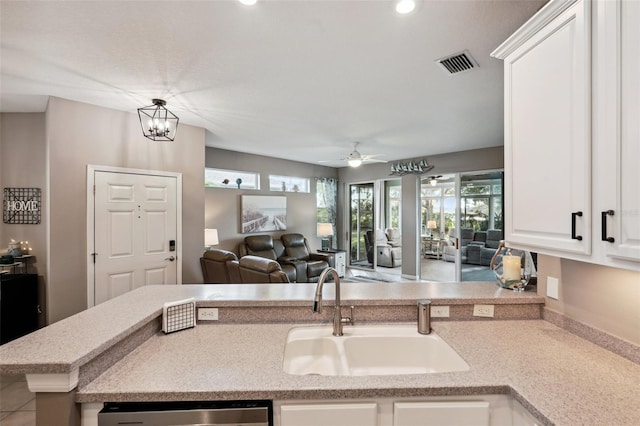 kitchen with white cabinets, dishwasher, kitchen peninsula, sink, and ceiling fan with notable chandelier