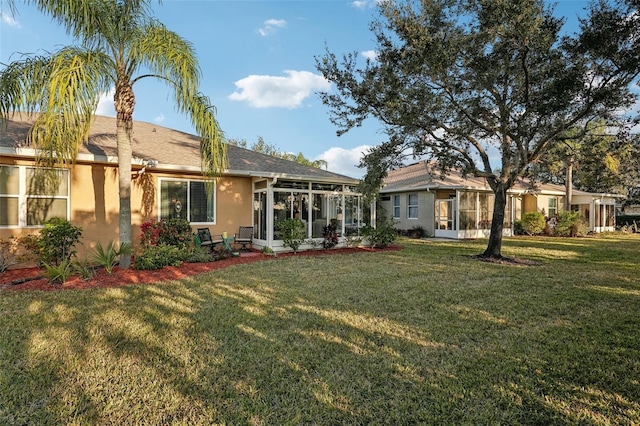 rear view of property with a yard and a sunroom