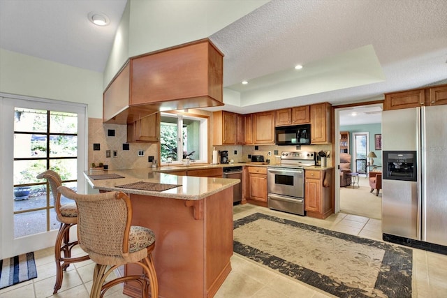 kitchen featuring stainless steel appliances, a kitchen bar, kitchen peninsula, and light tile patterned floors