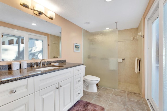 bathroom featuring tiled shower, vanity, and toilet