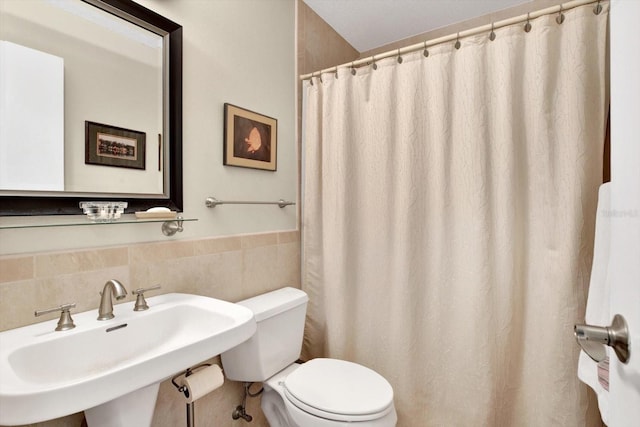 bathroom featuring tile walls, toilet, and sink