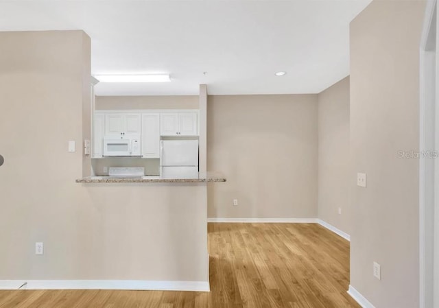 kitchen with white cabinets, light stone countertops, white appliances, and light wood-type flooring