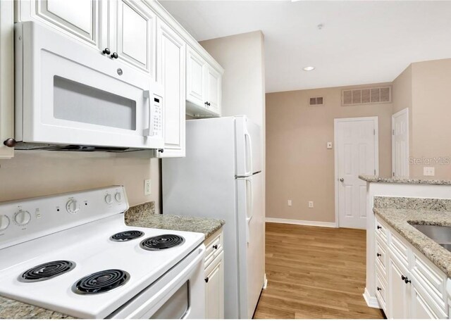 kitchen featuring white cabinets, light stone counters, white appliances, and light hardwood / wood-style flooring