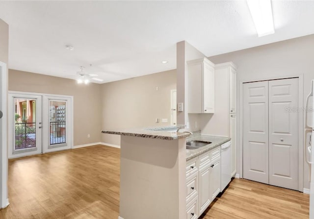 kitchen featuring kitchen peninsula, light stone counters, white cabinets, and ceiling fan