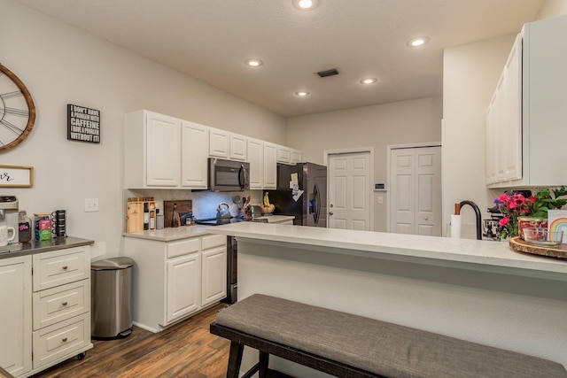 kitchen featuring kitchen peninsula, dark wood-type flooring, black fridge with ice dispenser, and white cabinets