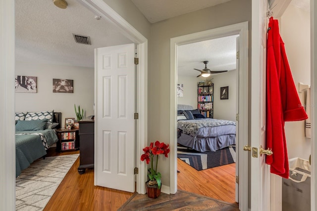 bedroom with ceiling fan, a textured ceiling, and wood-type flooring