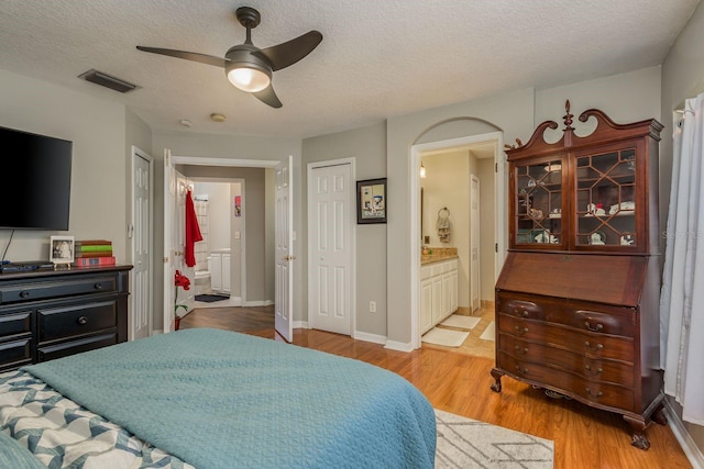 bedroom featuring light hardwood / wood-style floors, a textured ceiling, connected bathroom, and ceiling fan