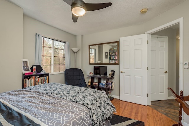 bedroom with ceiling fan, hardwood / wood-style floors, a closet, and a textured ceiling