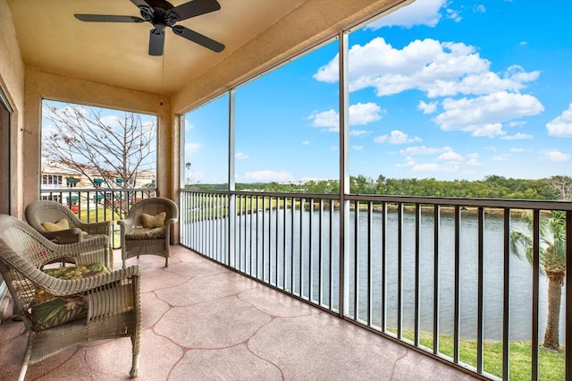 sunroom with ceiling fan and a water view