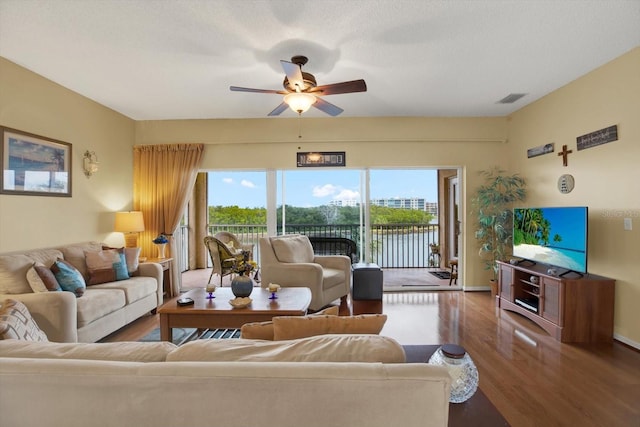 living room with a textured ceiling, ceiling fan, plenty of natural light, and dark hardwood / wood-style floors