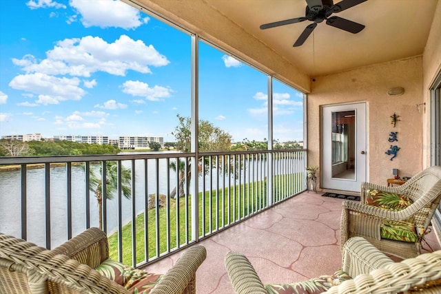 sunroom featuring ceiling fan and a water view