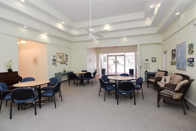 carpeted dining room with ceiling fan and a tray ceiling