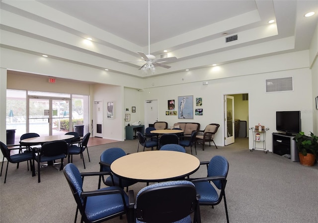 carpeted dining room featuring ceiling fan and a tray ceiling