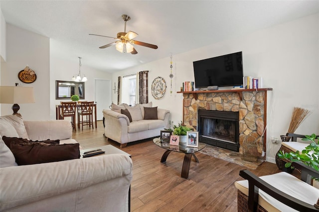 living room featuring ceiling fan with notable chandelier, hardwood / wood-style floors, lofted ceiling, and a fireplace