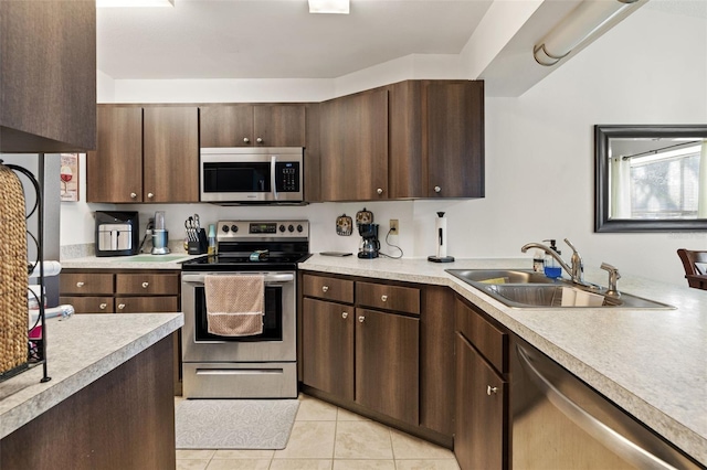 kitchen with sink, stainless steel appliances, light tile patterned floors, and dark brown cabinetry