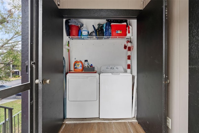 clothes washing area with separate washer and dryer and light hardwood / wood-style flooring