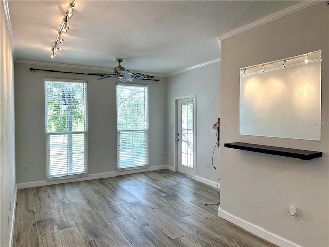 unfurnished room featuring ceiling fan, track lighting, a textured ceiling, crown molding, and light hardwood / wood-style flooring