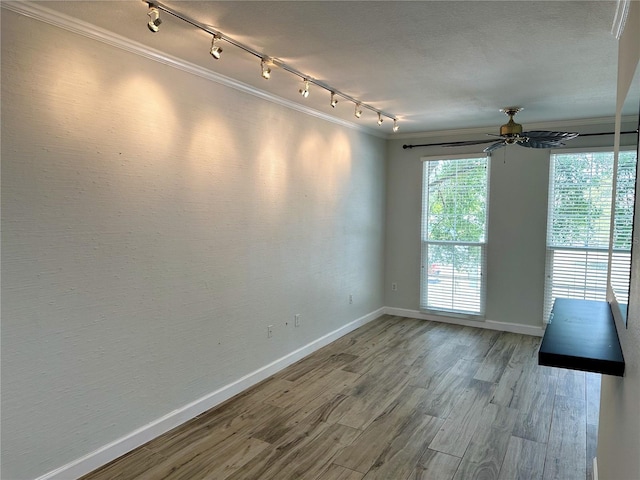 spare room featuring ceiling fan, wood-type flooring, crown molding, and track lighting