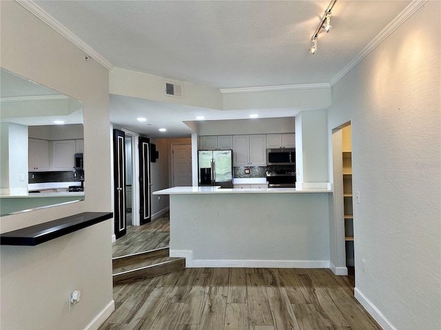 kitchen featuring track lighting, stainless steel appliances, decorative backsplash, kitchen peninsula, and gray cabinetry