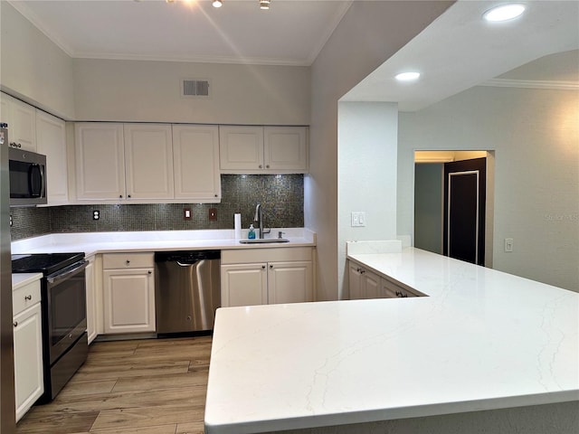 kitchen featuring white cabinets, stainless steel appliances, sink, kitchen peninsula, and crown molding