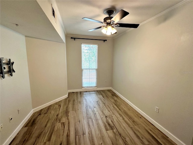 empty room featuring ceiling fan, light wood-type flooring, and crown molding