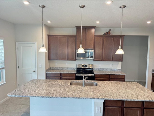 kitchen featuring light stone countertops, sink, stainless steel appliances, and a center island with sink