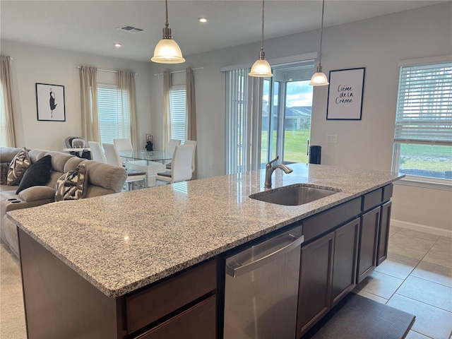 kitchen featuring light stone countertops, stainless steel dishwasher, dark brown cabinetry, sink, and pendant lighting