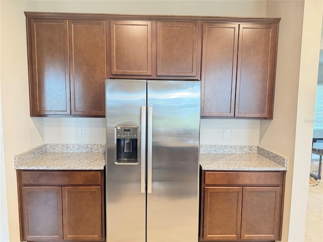 kitchen featuring stainless steel fridge with ice dispenser and light stone counters