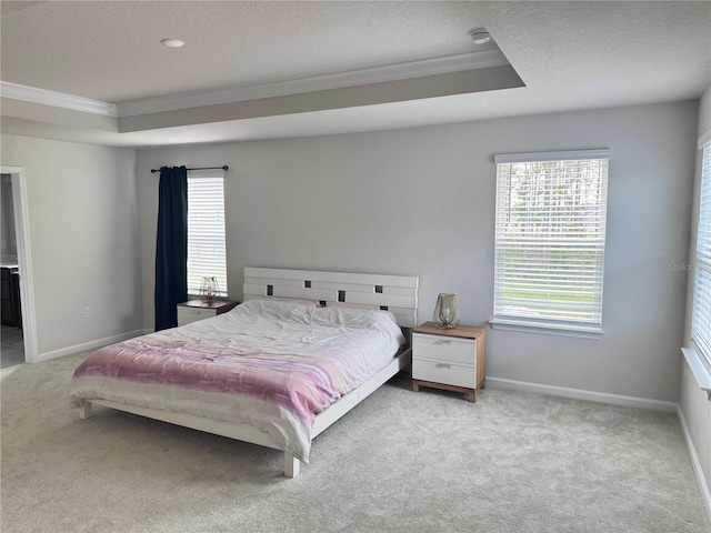 bedroom featuring a textured ceiling, ornamental molding, light carpet, and a tray ceiling